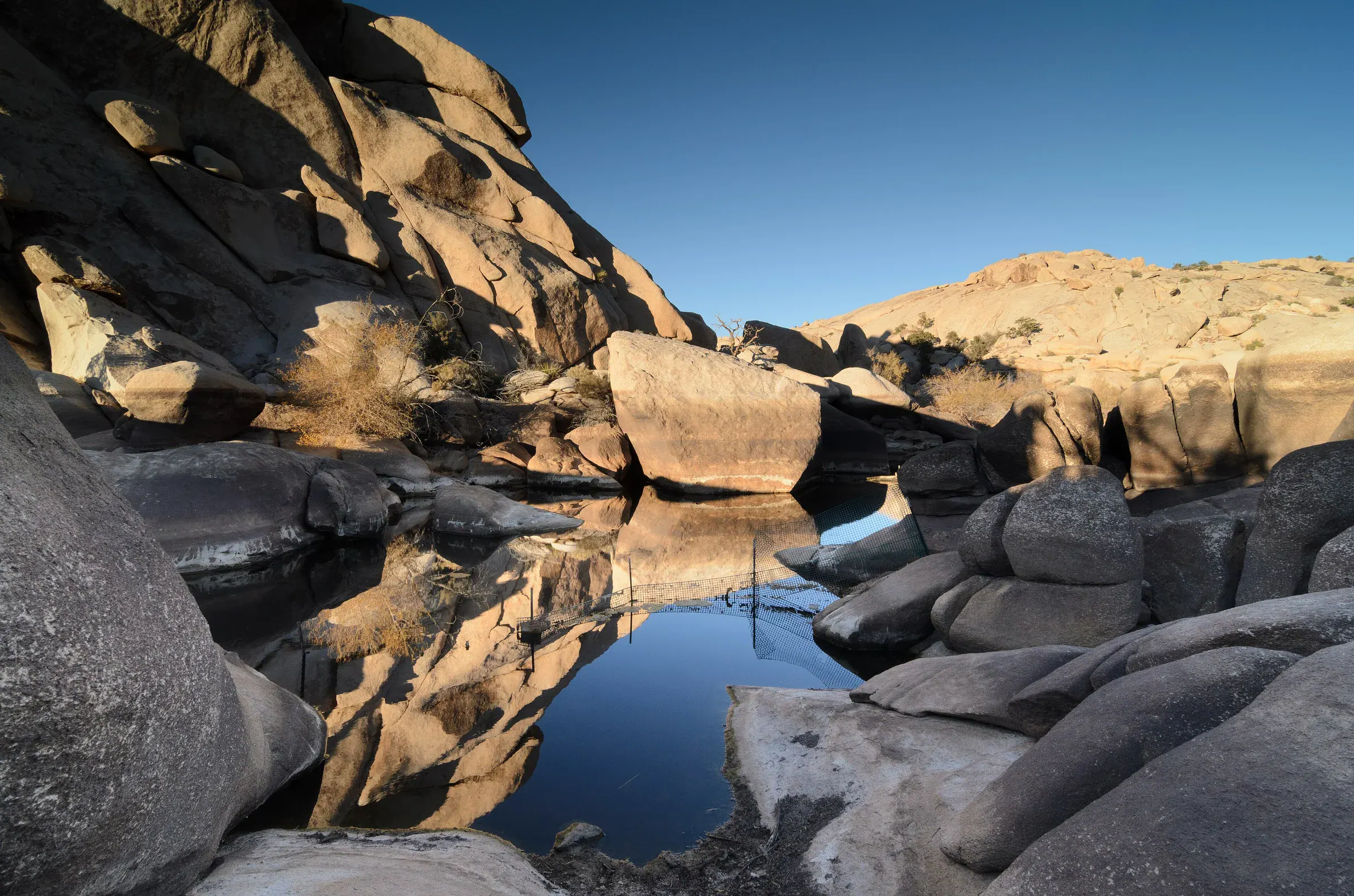 Barker Dam reservoir surrounded by rocks and desert vegetation