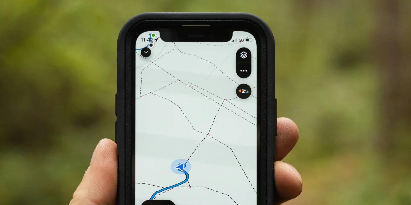 A hiker holding a phone with an offline trail map open